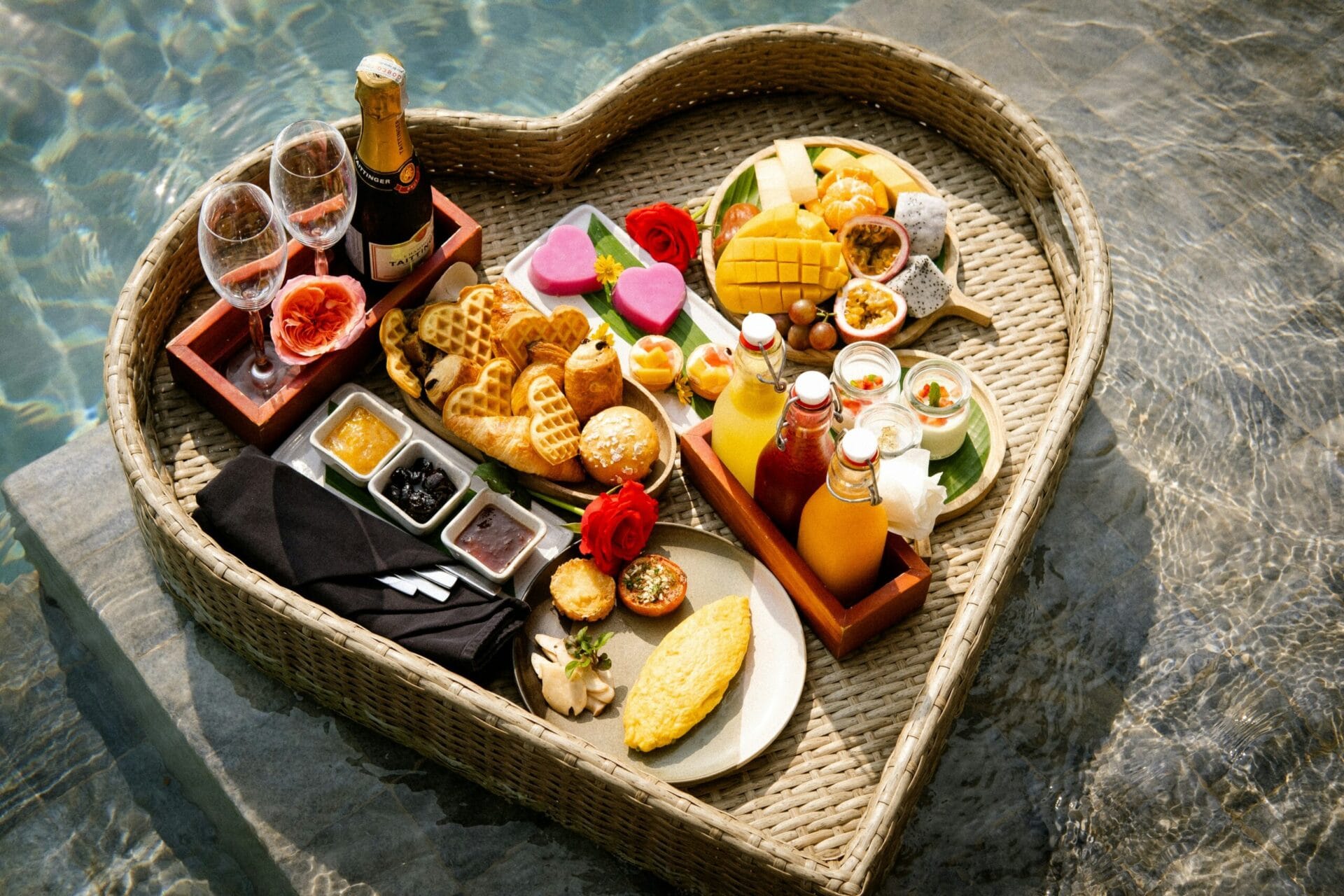 A heart shaped tray filled with food next to a pool